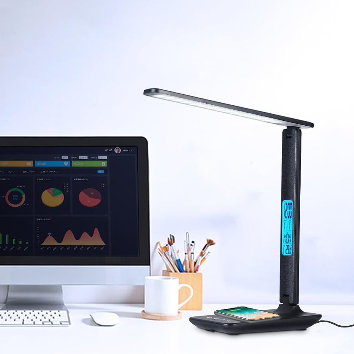 Eine schwarze Schreibtischlampe mit digitaler Anzeige, Telefon und Bürobedarf.