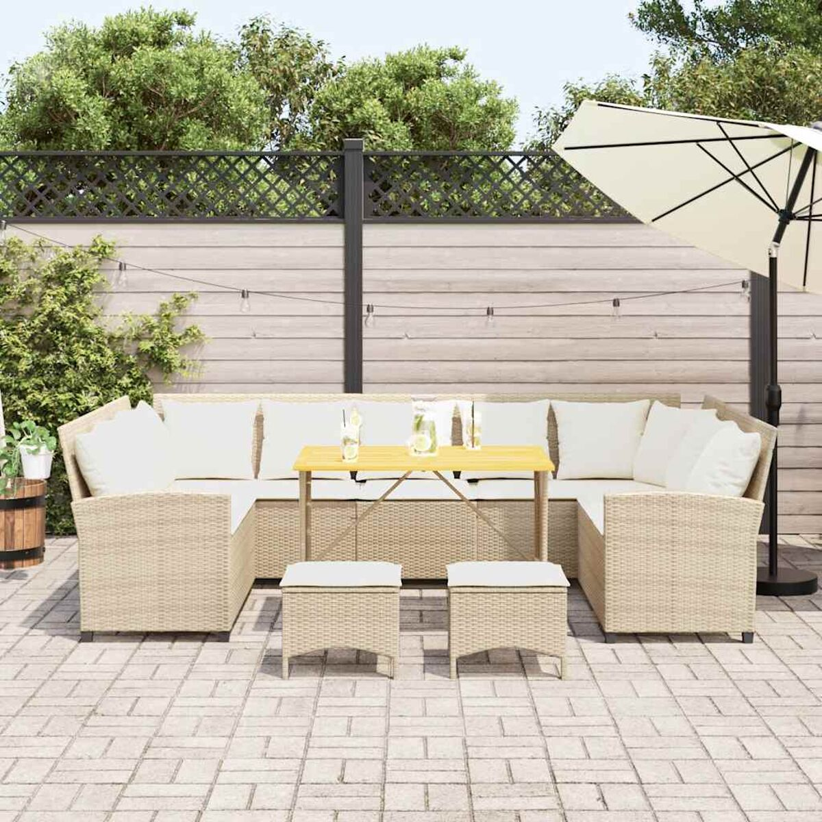Set patio: divano in vimini, tavolo e pouf, con ombrellone in giardino.