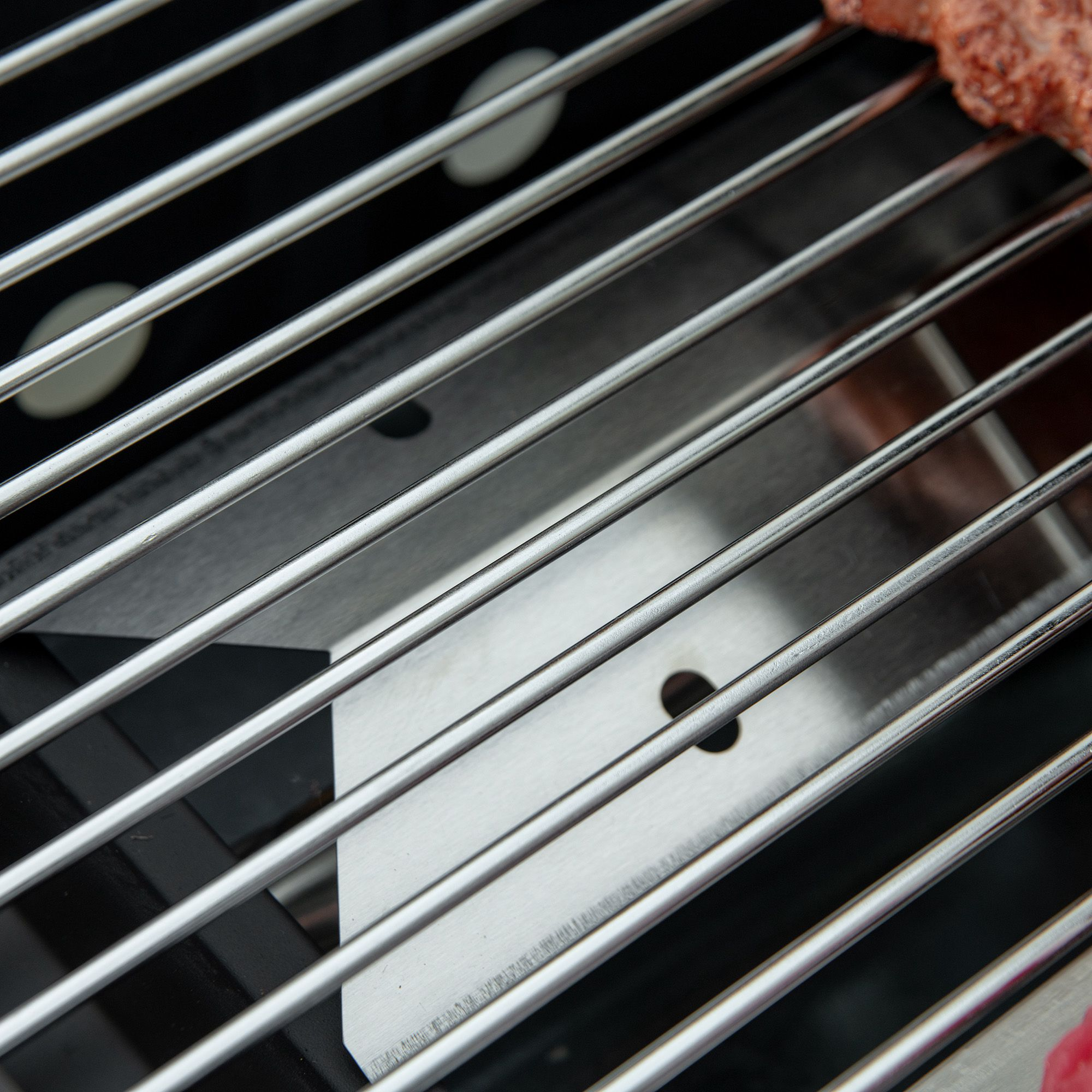 Nahaufnahme eines Grills. Edelstahlstangen mit schwarzem Hintergrund. Metalloberfläche.
