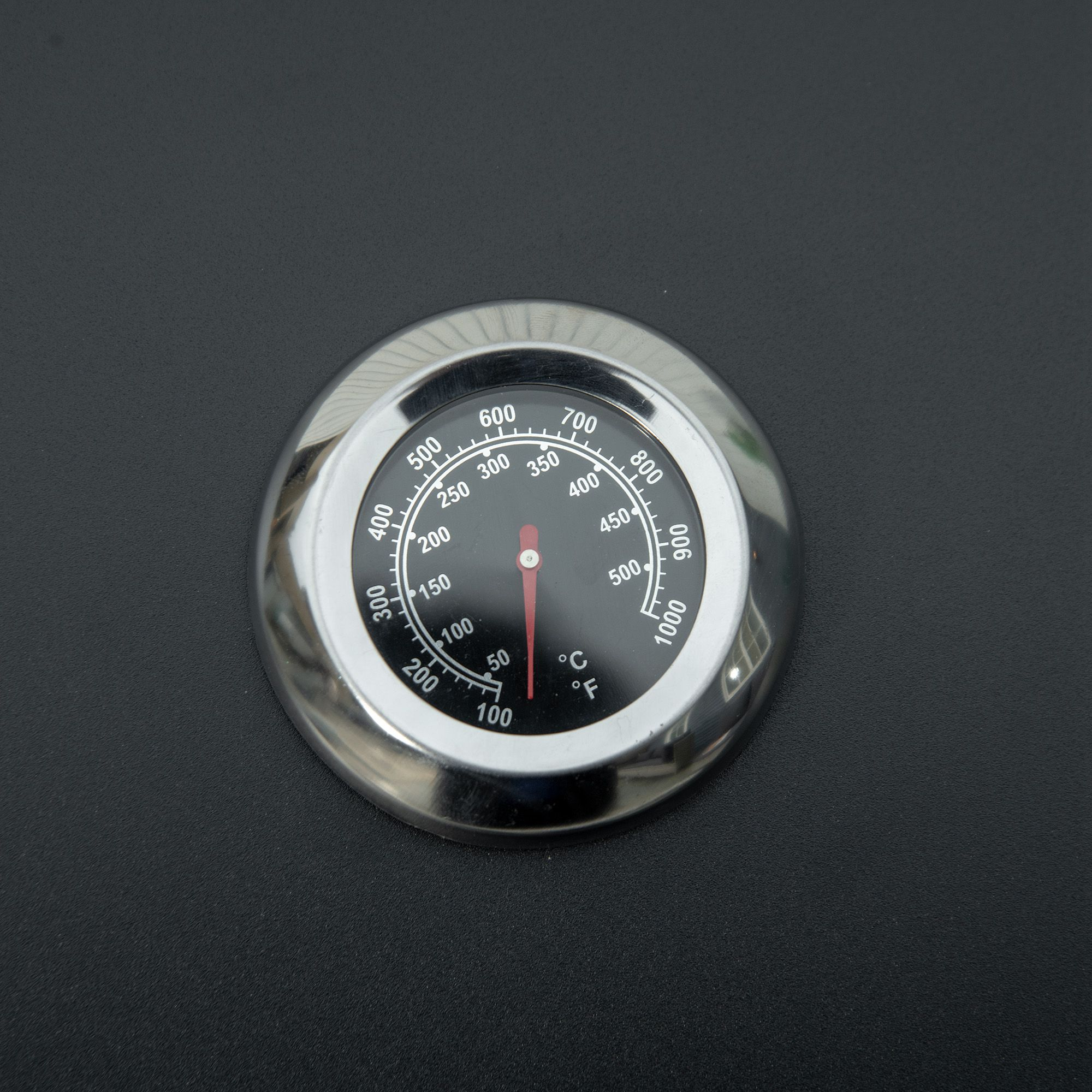 Nahaufnahme eines schwarzen Grillthermometers mit Temperaturmarkierungen und rotem Zeiger.