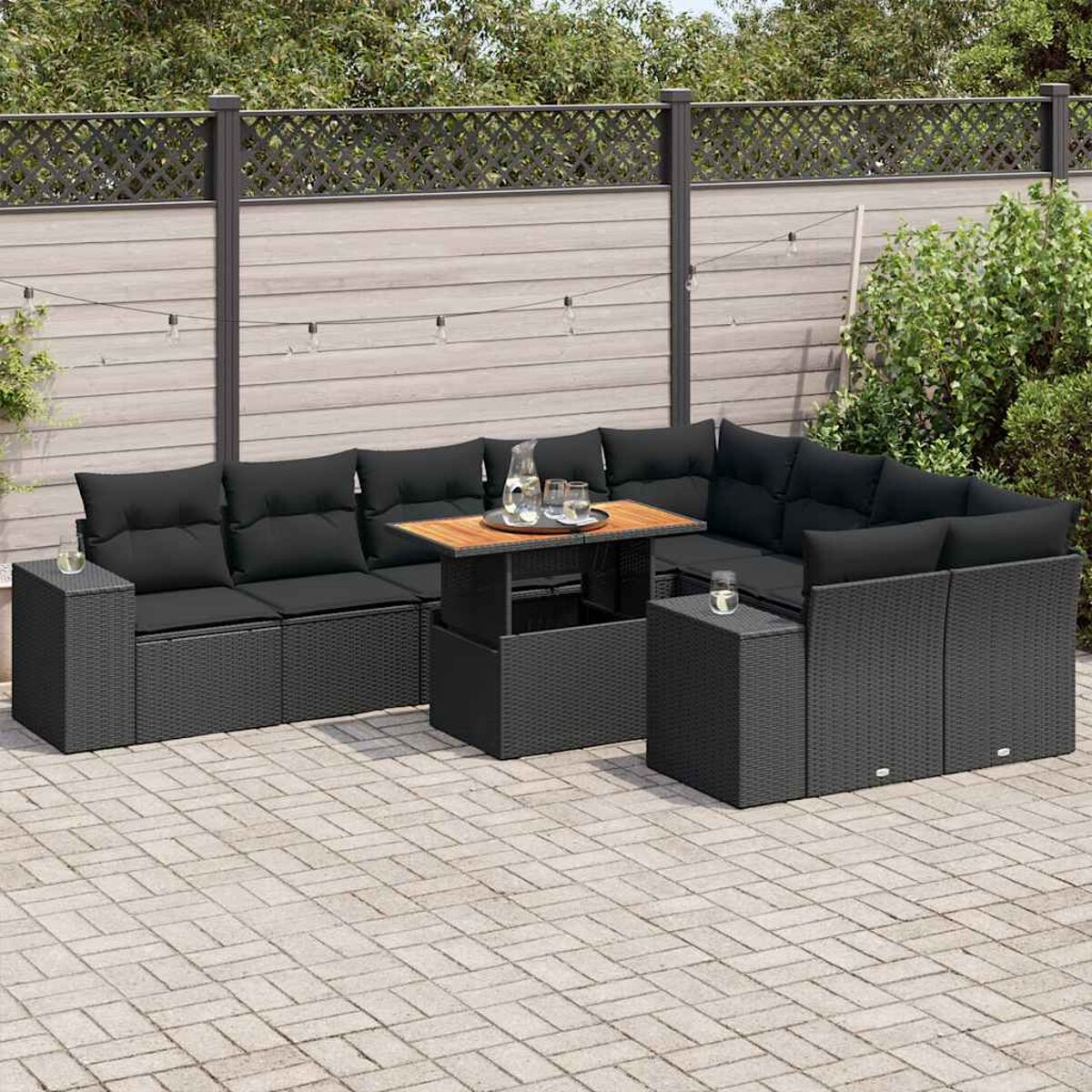 Schwarzes Outdoor-Geflechtmöbel-Set. Enthält Sofa, Tisch und zwei Beistelltische. Gepflasterte Terrasse.