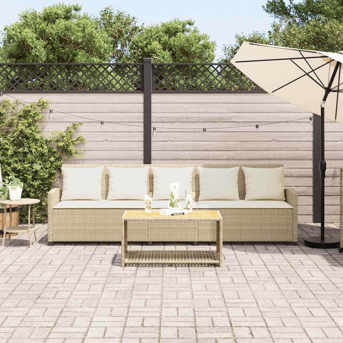 Scena patio esterno con divano beige, tavolino e ombrellone. Recinzione e verde sullo sfondo.