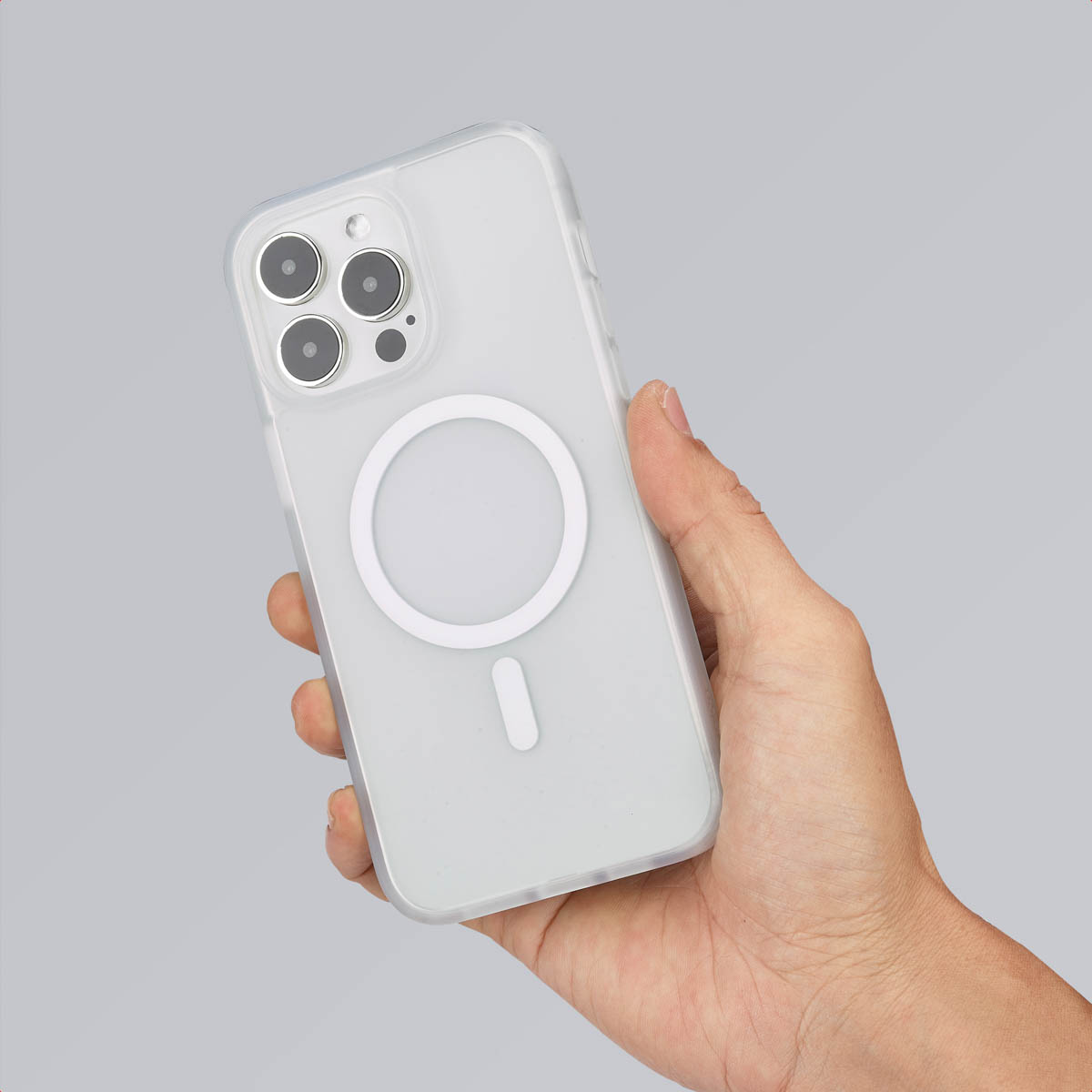 Main tenant un téléphone blanc à l'intérieur d'une coque de protection transparente. L'étui a un cercle magnétique.