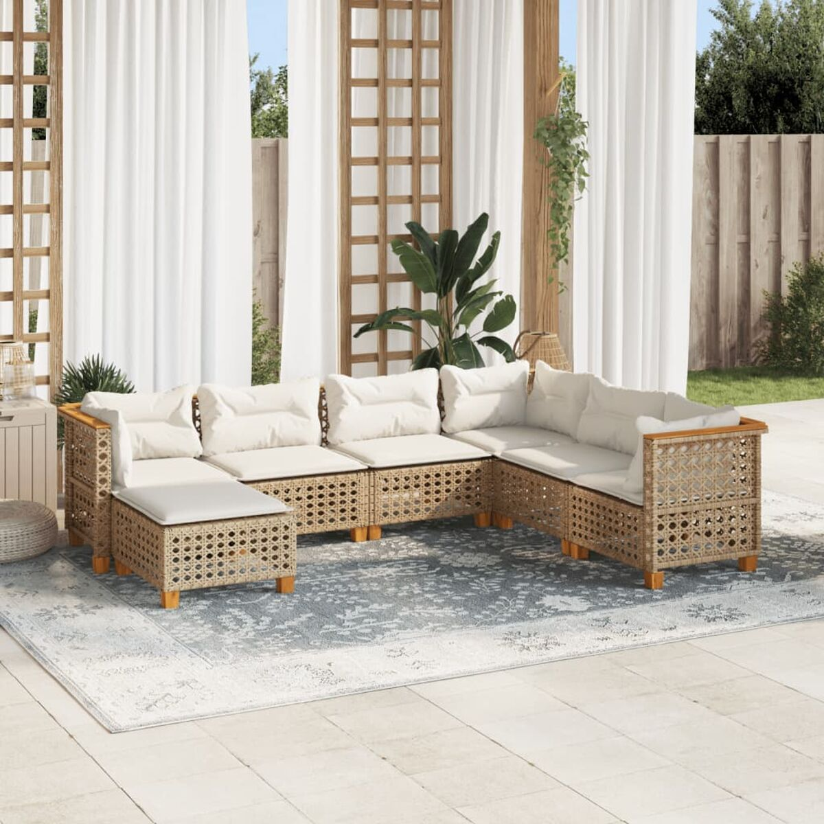Set di sedute per esterni: divano in rattan con cuscini chiari su un tappeto fantasia.