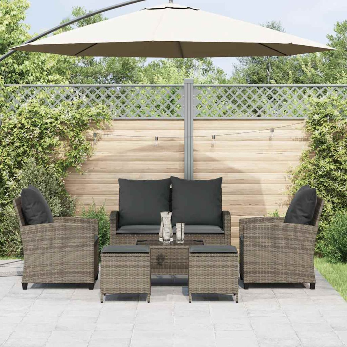 Set divano in rattan con ombrellone, tavolo e due sgabelli in giardino.