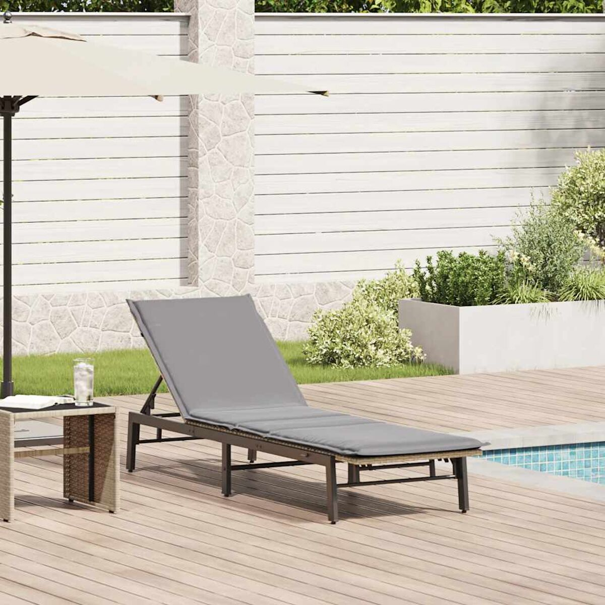 Una sedia a sdraio grigia vicino a una piscina. Un tavolino con un bicchiere d'acqua è accanto alla sedia.