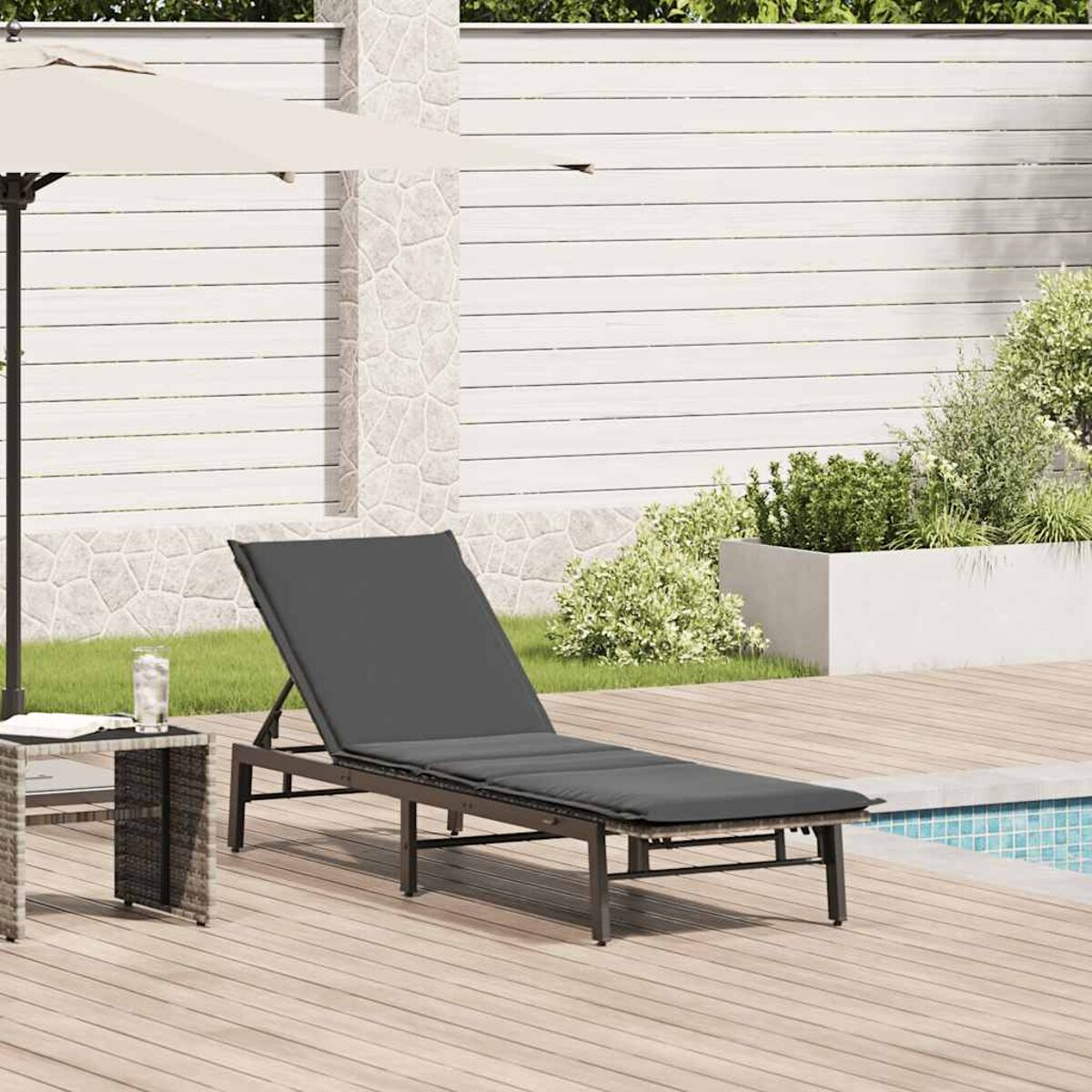 Chaise longue a bordo piscina. Cuscino grigio scuro, telaio metallico, ombrellone beige.