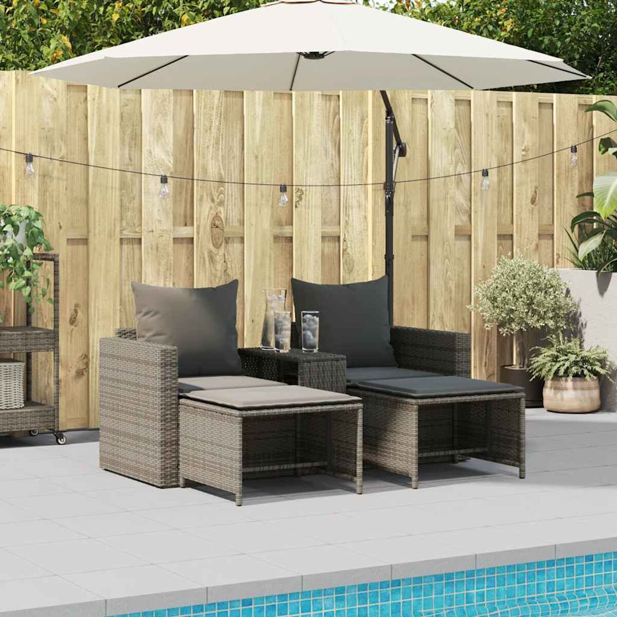 Set patio esterno con due sedie, pouf, tavolo e ombrellone. Piscina sullo sfondo.
