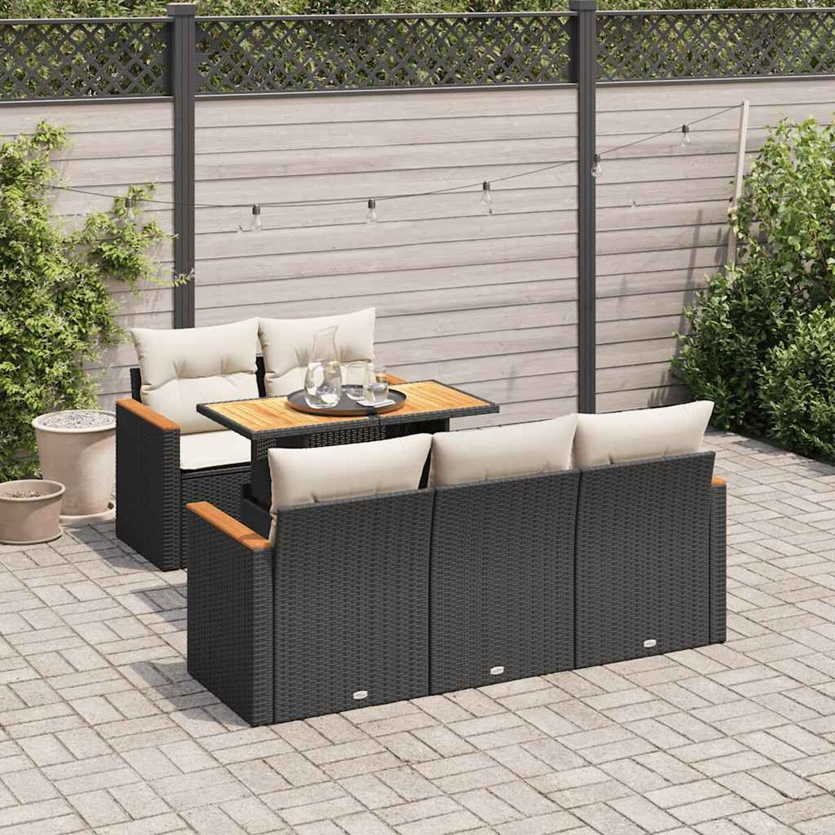 Set di mobili da esterno: divano e sedia con cuscini, tavolo su un patio pavimentato.