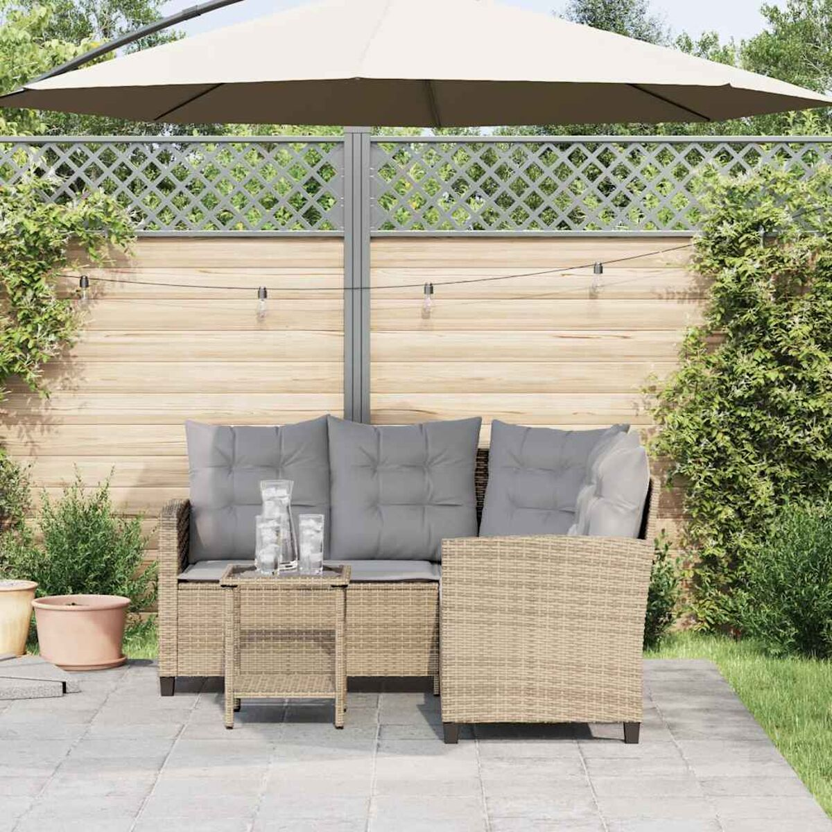 Set di mobili da patio con ombrellone. Divano e sedie in vimini con cuscini grigi.