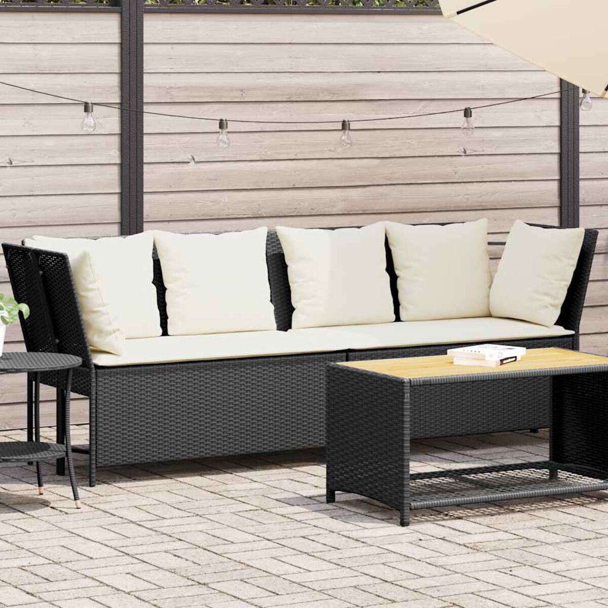 Divano in rattan da esterno con cuscini, tavolo e sfondo neutro.