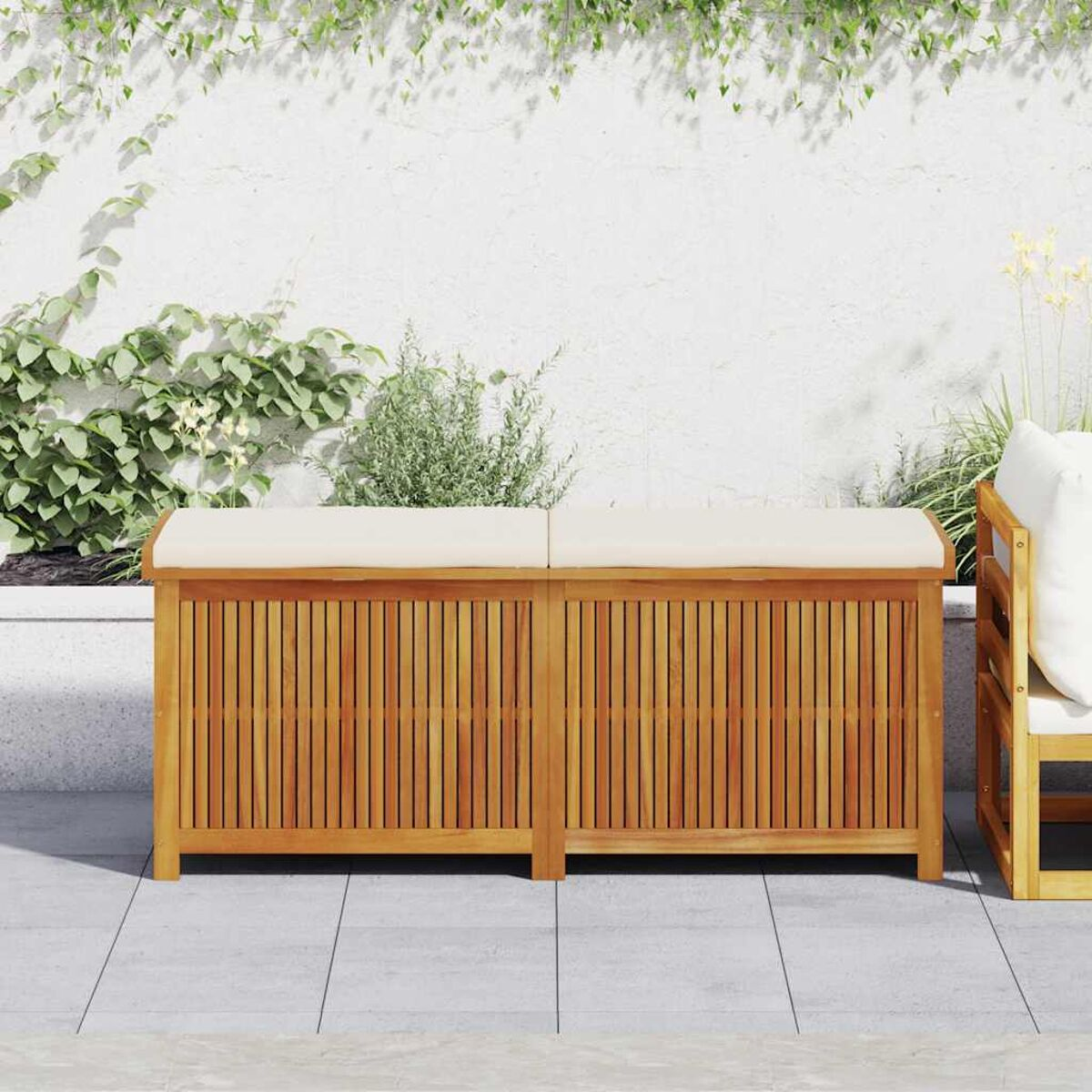 Zwei Holz-Aufbewahrungsbänke mit Kissen auf einer Terrasse mit Pflanzen.
