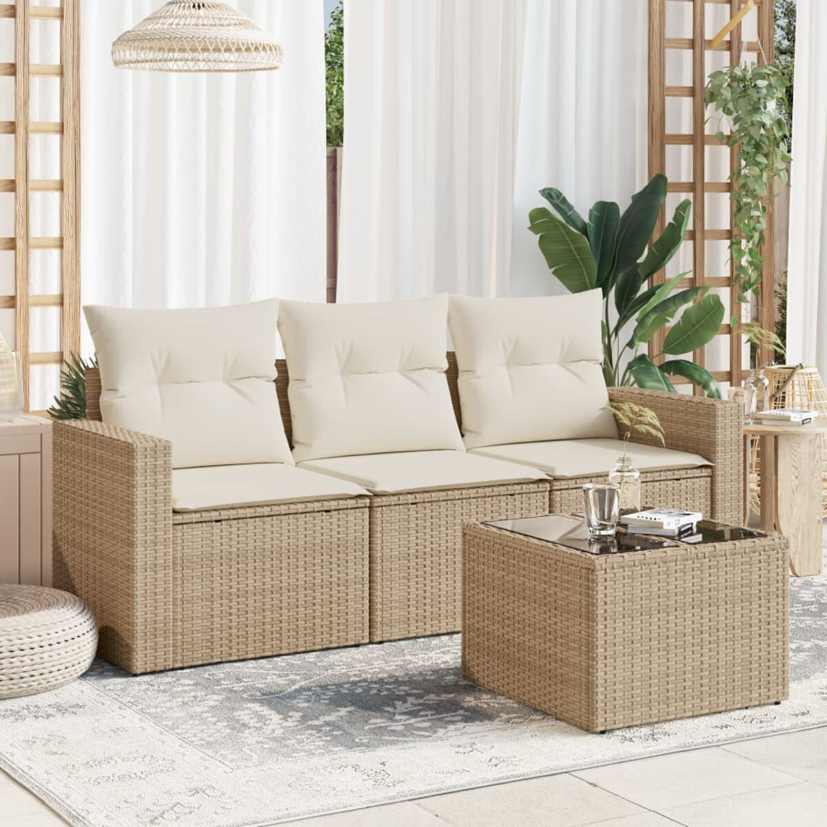 Un divano e un tavolino in rattan beige su un patio, con piante e un tappeto.