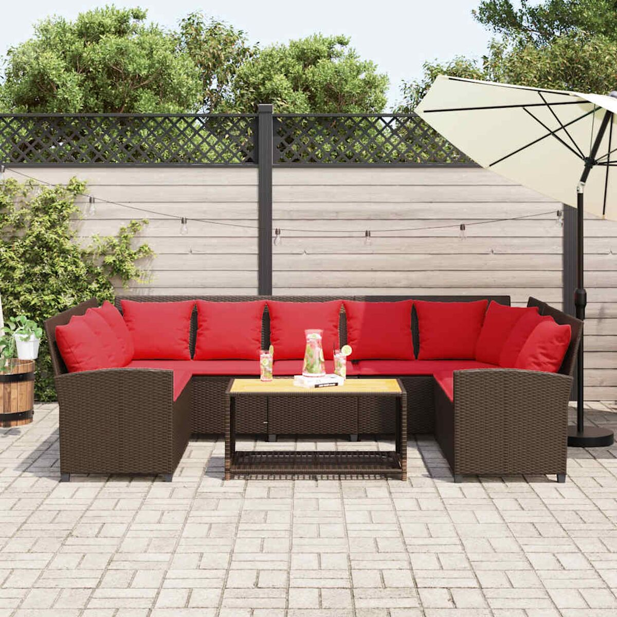 Set patio esterno con cuscini rossi, tavolo e ombrellone.