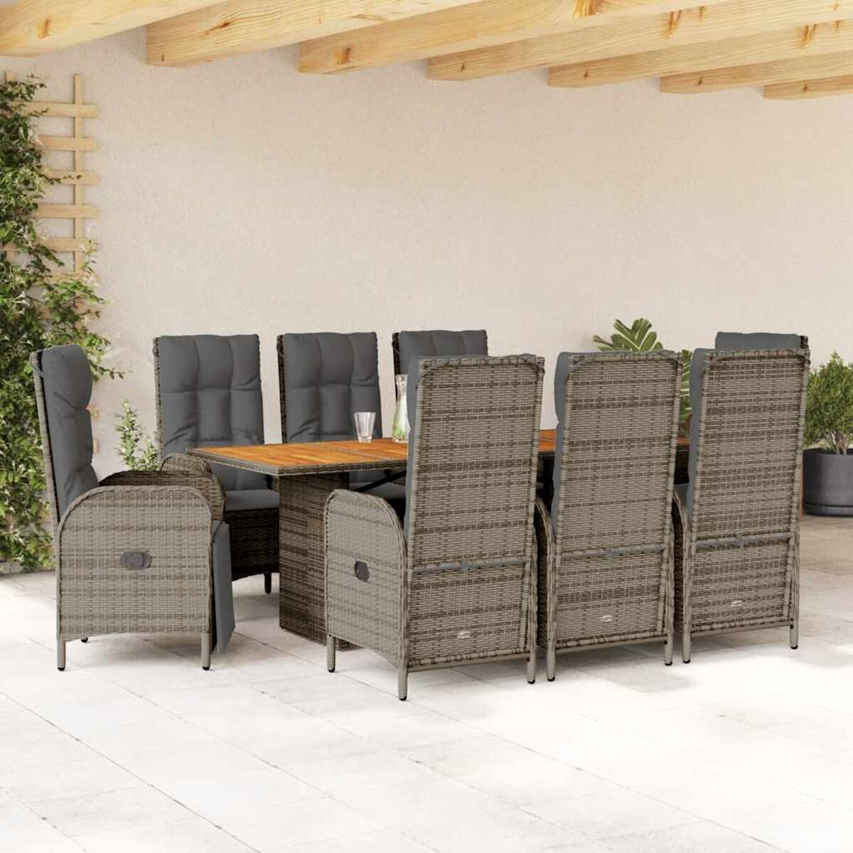 Essgruppe aus Rattan im Freien, mit Holztisch, grauen Kissen und Pflanzen.