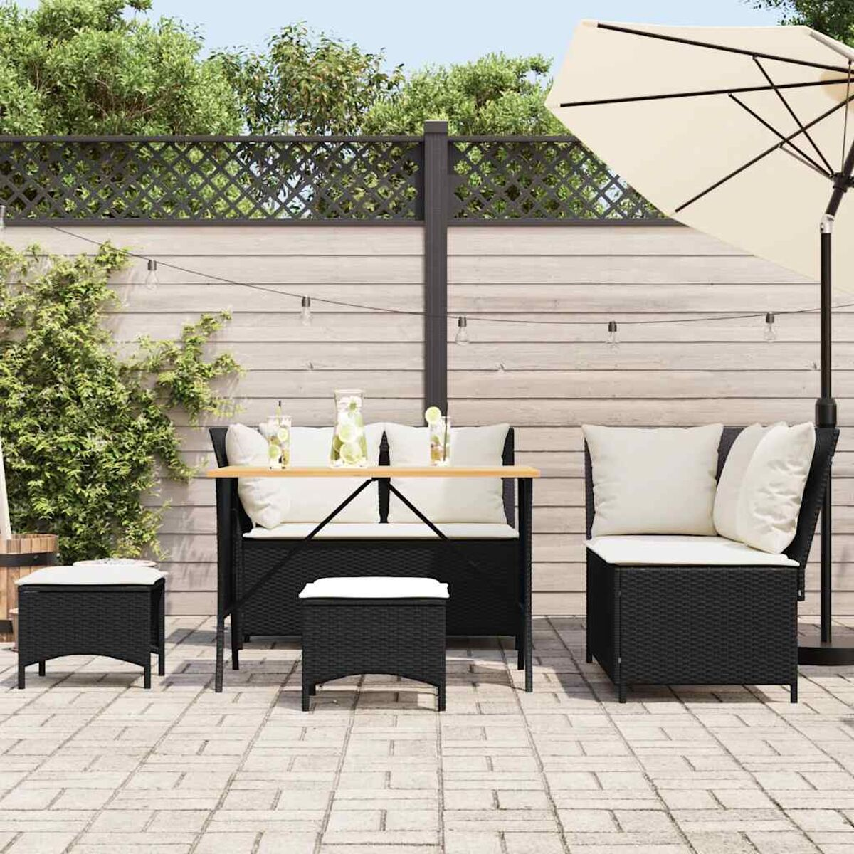 Terrassenset: schwarze Korbmöbel, Tisch, Stühle und Sonnenschirm auf Ziegelpflaster.