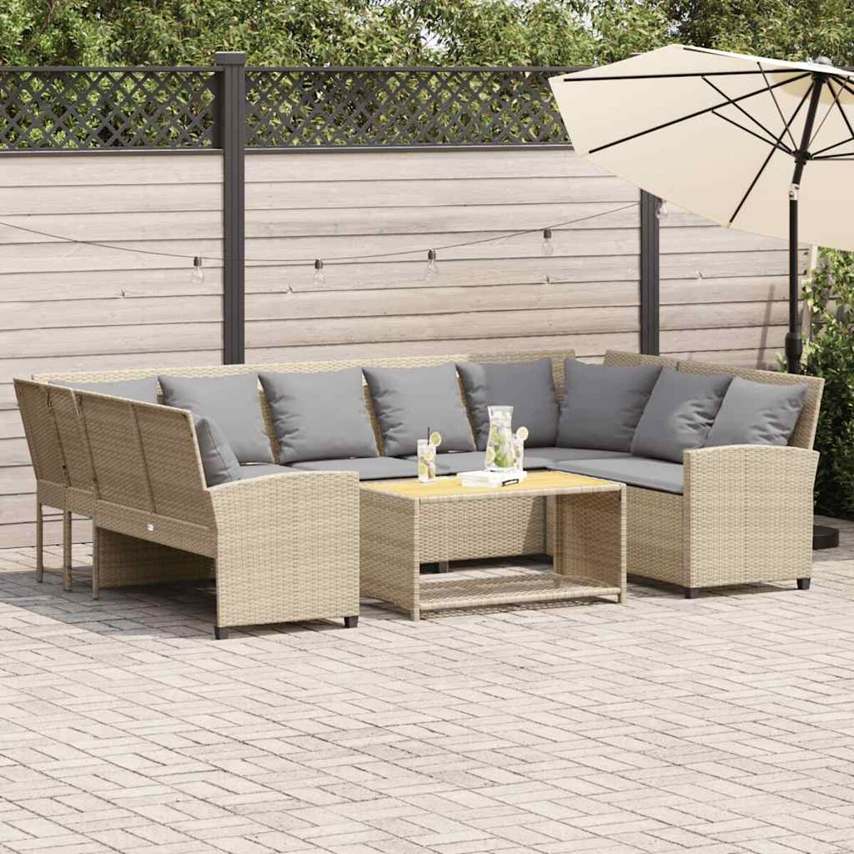 Un divano angolare in rattan da esterno con cuscini grigi e un tavolo in legno, con un'ambientazione da patio.