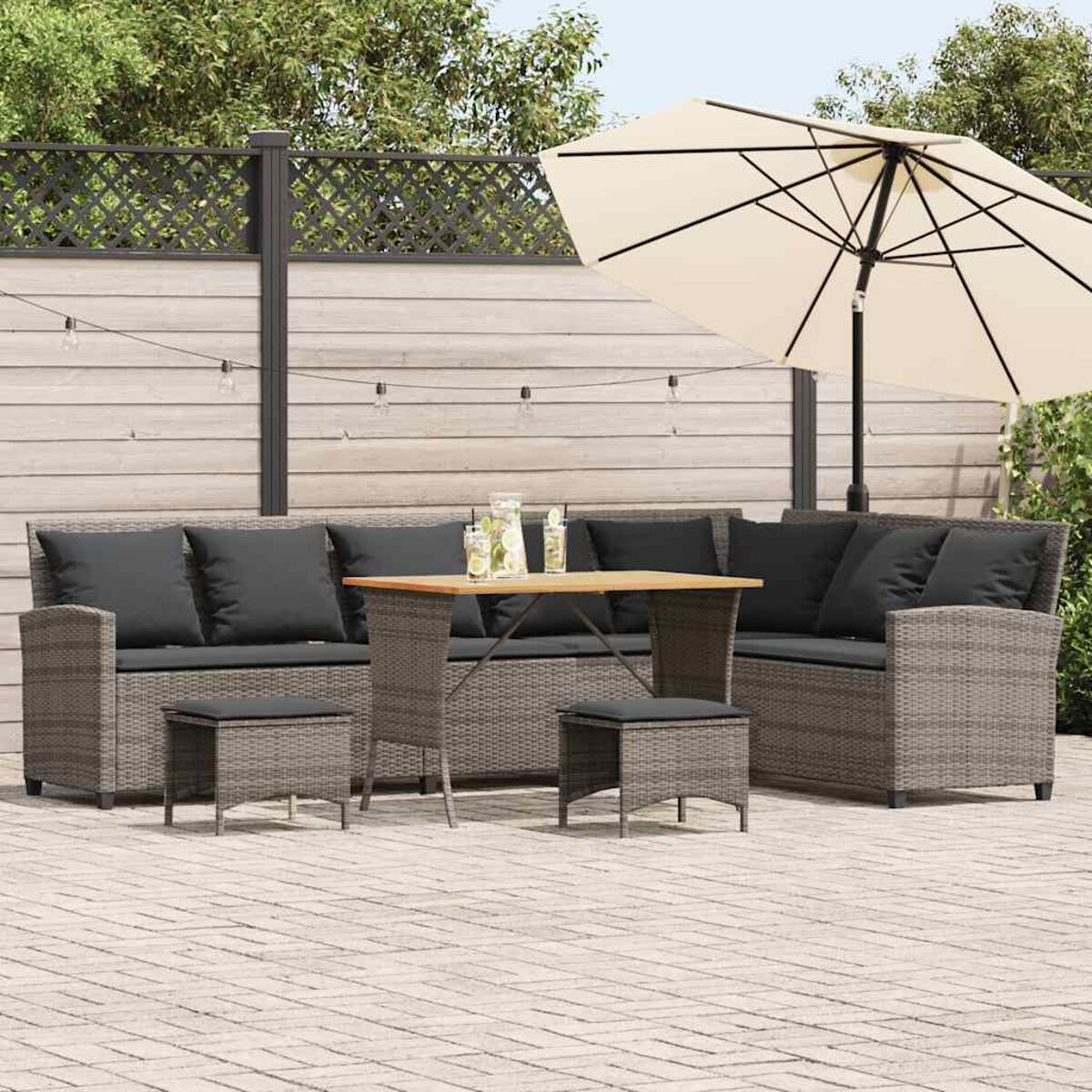 Set di mobili in rattan per esterni con tavolo, sedie e cuscini, sotto un ombrellone beige.