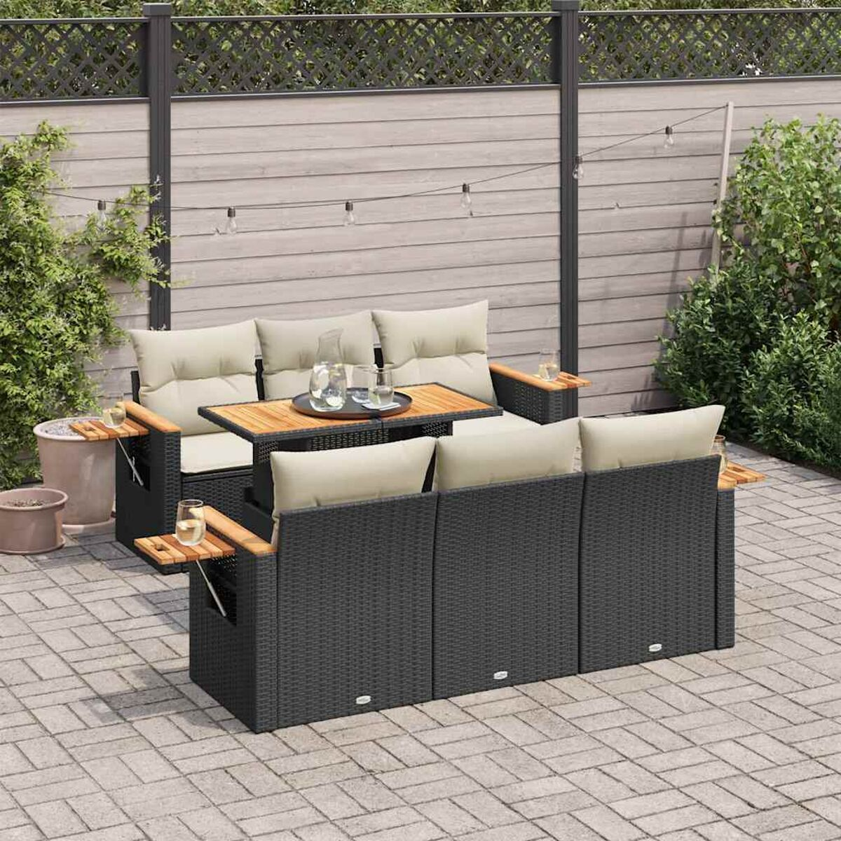 Outdoor-Rattan-Sofagarnitur mit Tisch. Schwarzes Rattan, Holzakzente, beige Kissen und eine gepflasterte Terrasse.