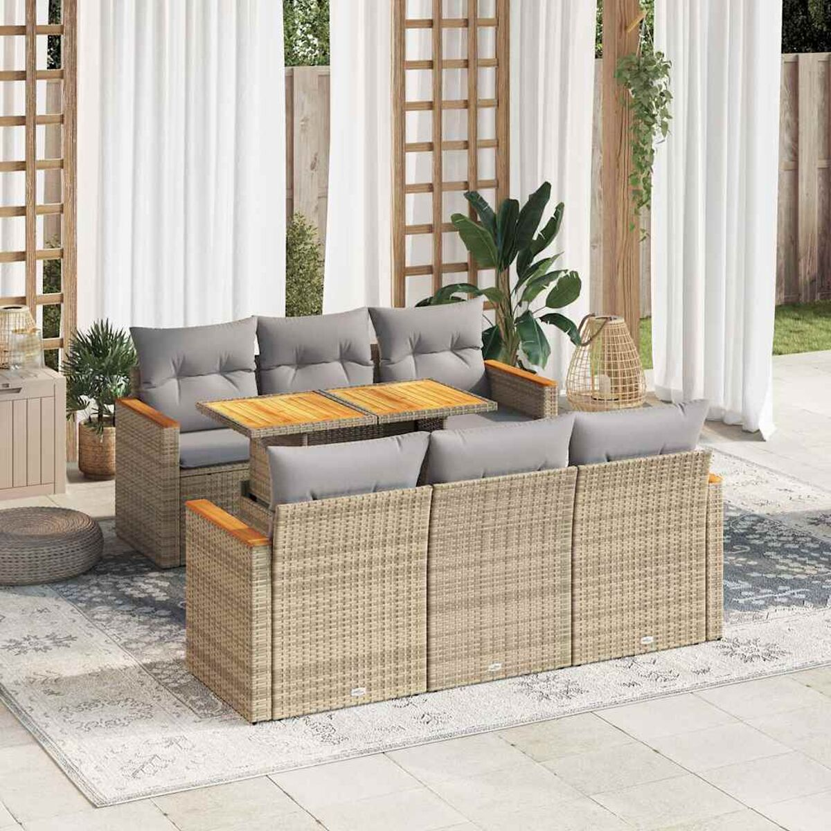 Ein Ecksofa aus Rattan für draußen mit grauen Kissen, Holztischen und einem Teppich.
