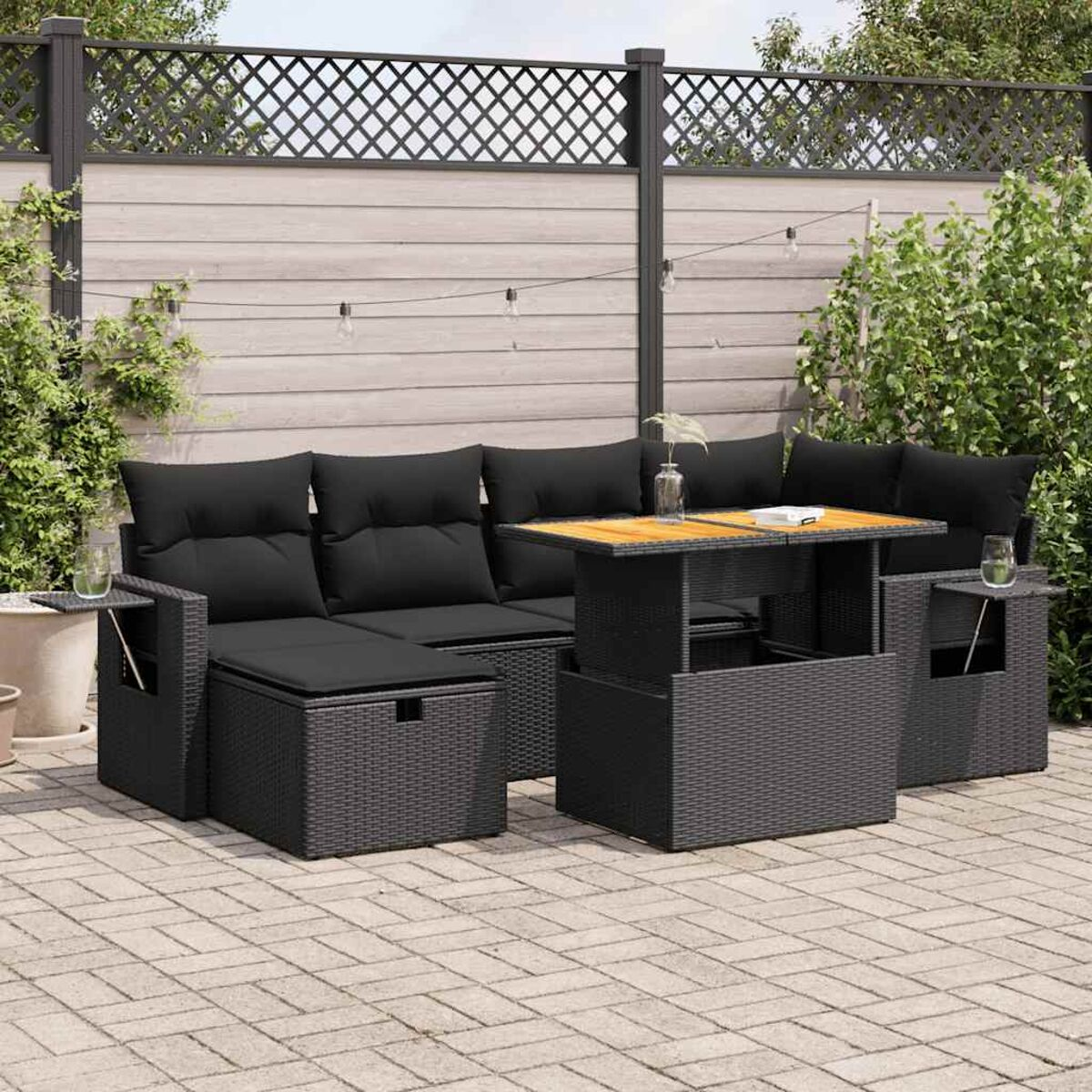 Gartenmöbel-Set mit schwarzen Kissen und Tisch.