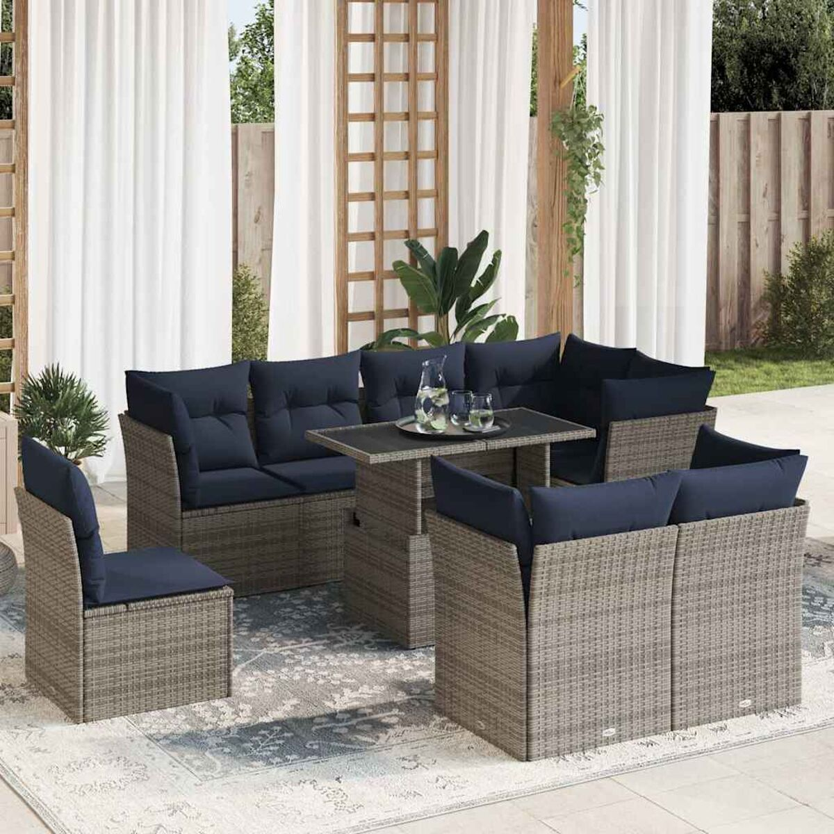 Un set da patio esterno con cuscini blu, disposto su un tappeto, con tende sullo sfondo.