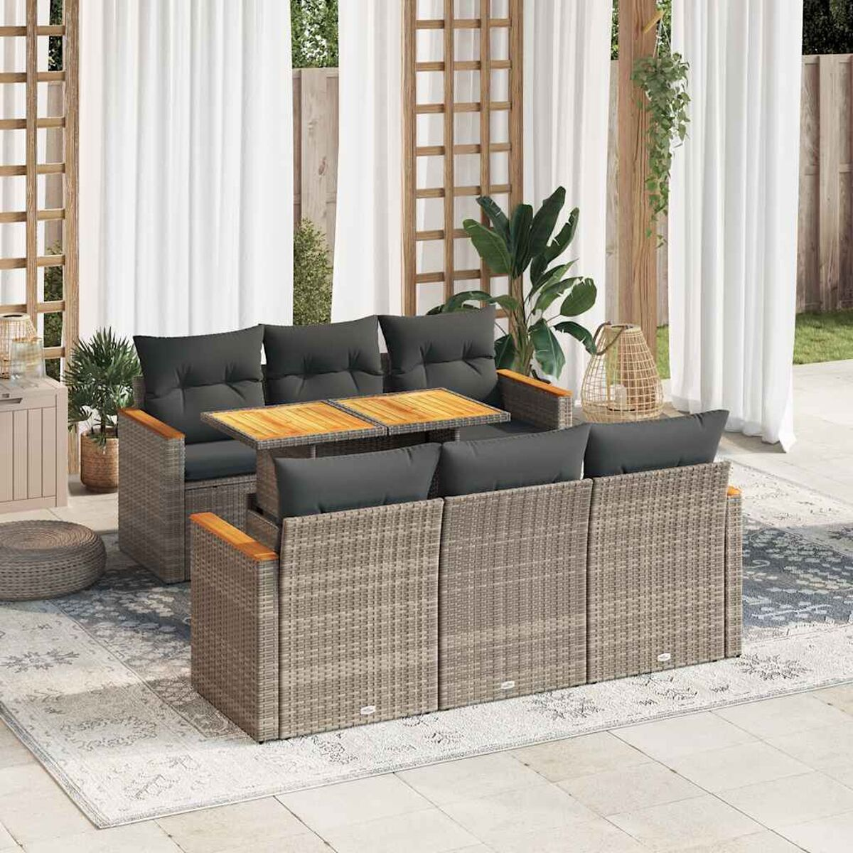 Set divani in rattan da esterno con cuscini grigi. Sono presenti anche un tavolo e cuscini. Tende trasparenti sullo sfondo.