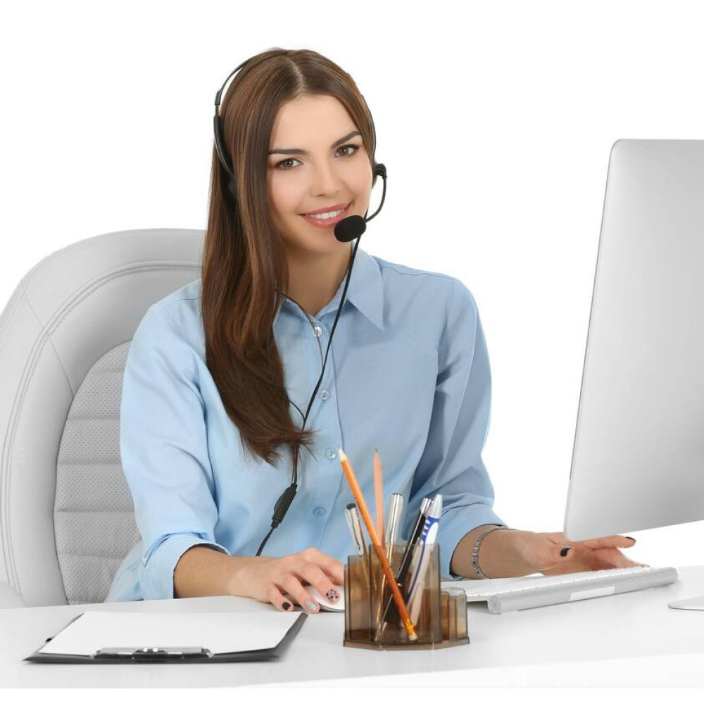 Donna con auricolare, sorridente a uno schermo del computer. Cancelleria davanti.