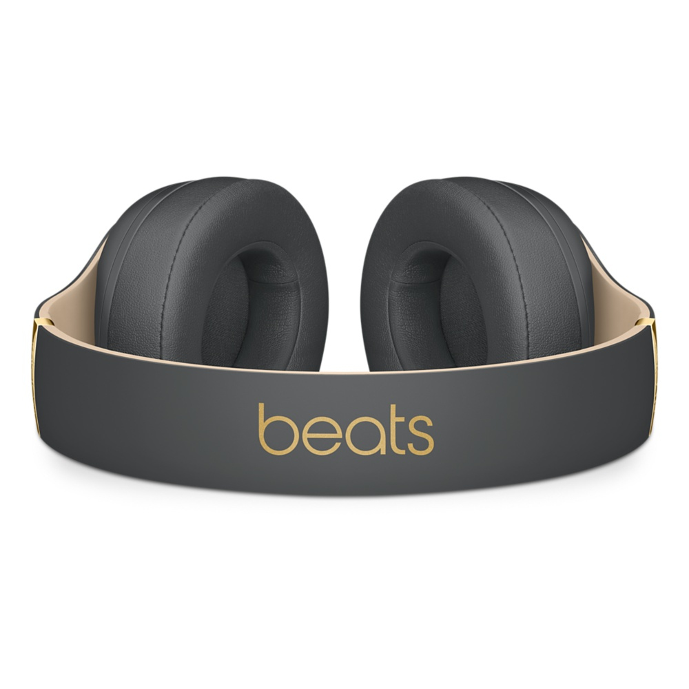 Słuchawki Beats, otwarte. Czarne nauszniki, złote logo i czarna opaska. Białe tło.