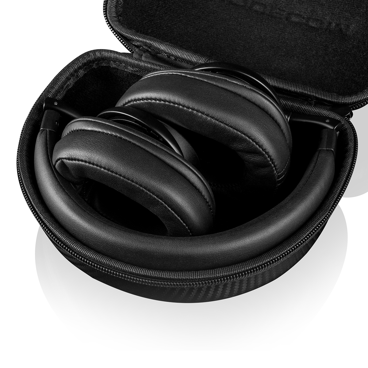 Złożone czarne słuchawki w czarnym etui. Etui jest otwarte. Białe tło, zbliżenie.