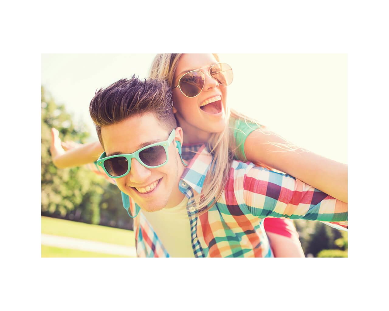 Un uomo dà a una donna un passaggio a cavallina, entrambi sorridenti. Giorno di sole.