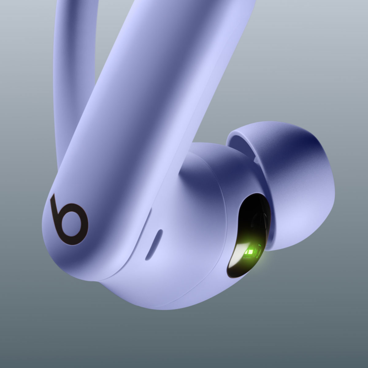 Zbliżenie lawendowych bezprzewodowych słuchawek. Widoczne logo Beats. Zielone światło.