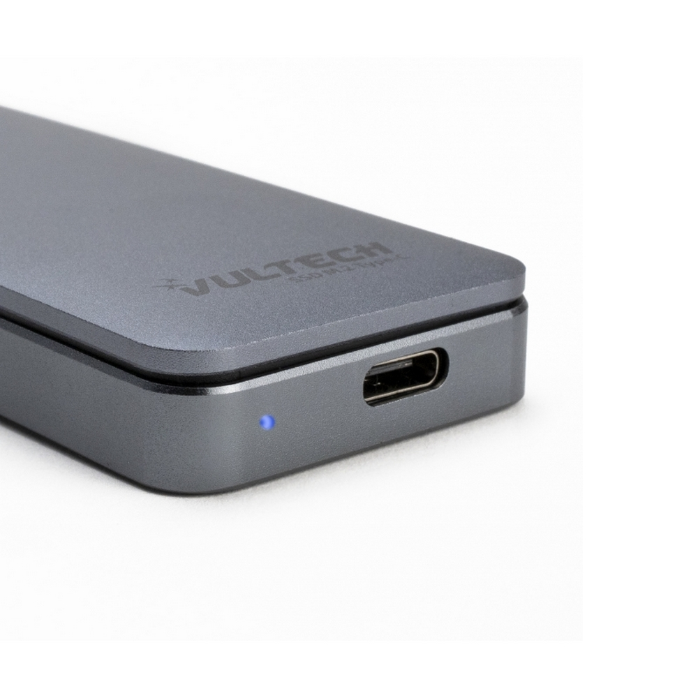 Un dispositivo rettangolare grigio con porta USB-C e luce blu su una superficie bianca.