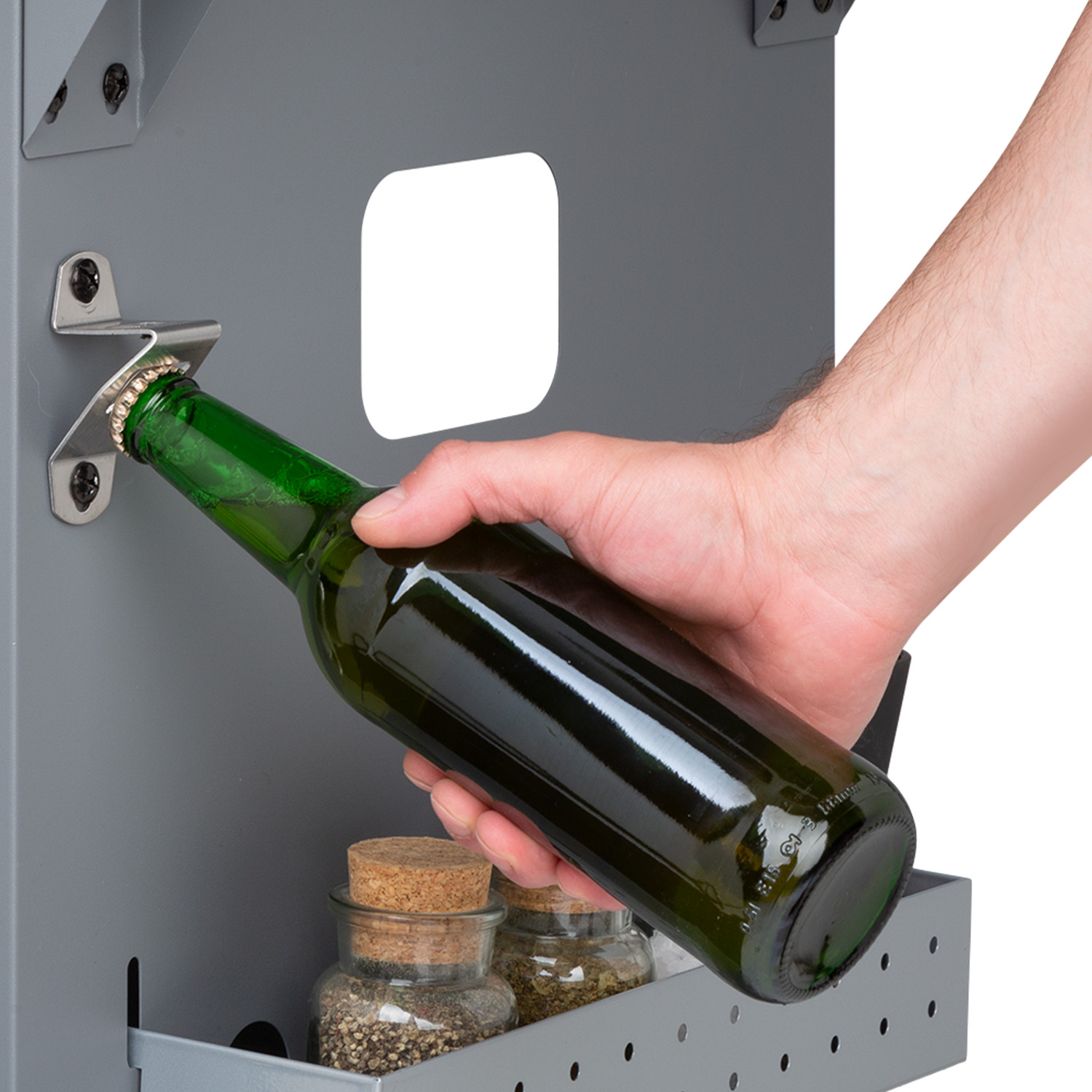 Eine Hand, die eine grüne Flasche über einem Flaschenöffner hält, darunter Gewürzflaschen.
