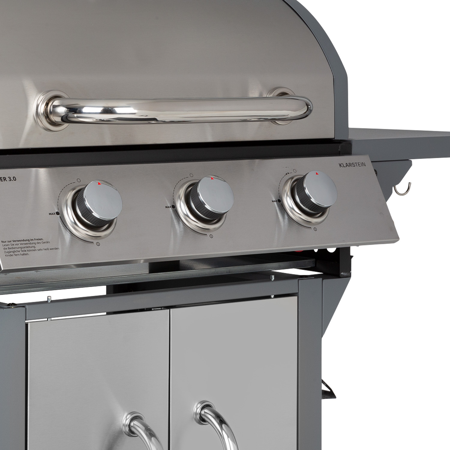 Nahaufnahme eines Grills mit drei silbernen Knöpfen und einem Griff, sowie zwei Türen.