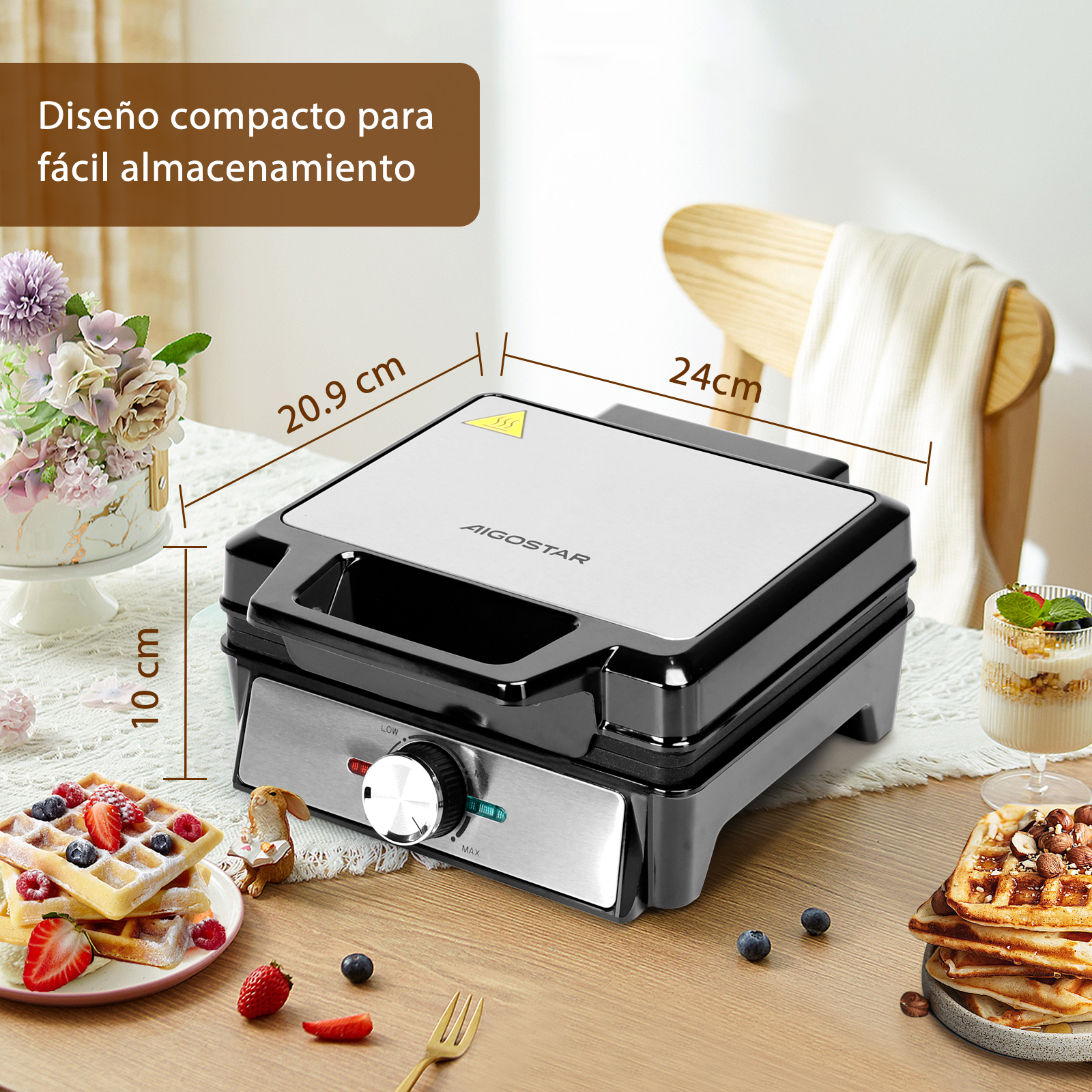 Una gofrera negra y plateada sobre una mesa con gofres y aderezos. Se muestran las dimensiones.