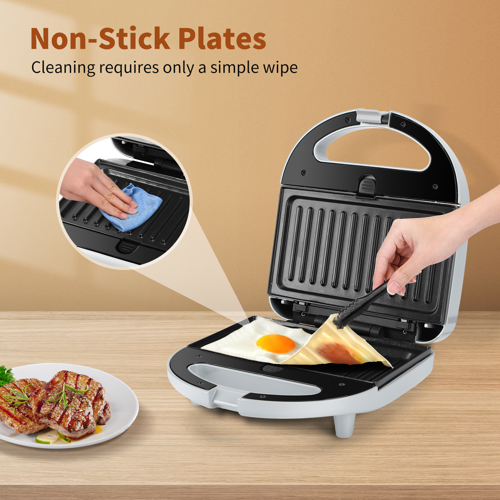 Sandwichmaker mit einem Ei, das kocht. Eine Hand wischt mit einem Tuch. Gebratene Steaks daneben.