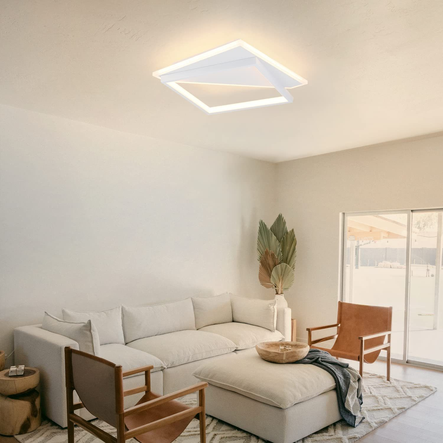 Salón con muebles blancos y una lámpara de techo geométrica blanca.