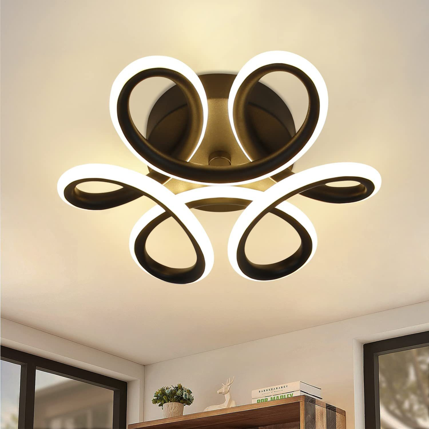 Lampa sufitowa o abstrakcyjnym wzorze emitująca białe światło, nad pomieszczeniem z meblami.