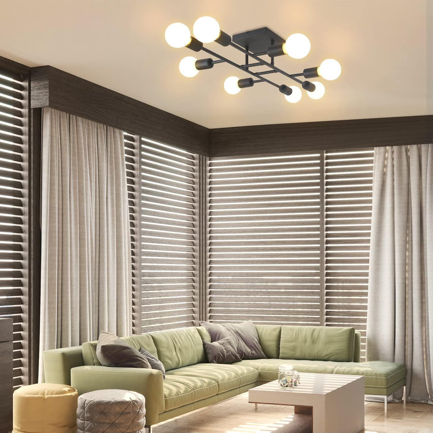 Sala de estar moderna con sofá verde, mesa blanca y una lámpara de techo negra con bombillas redondas.