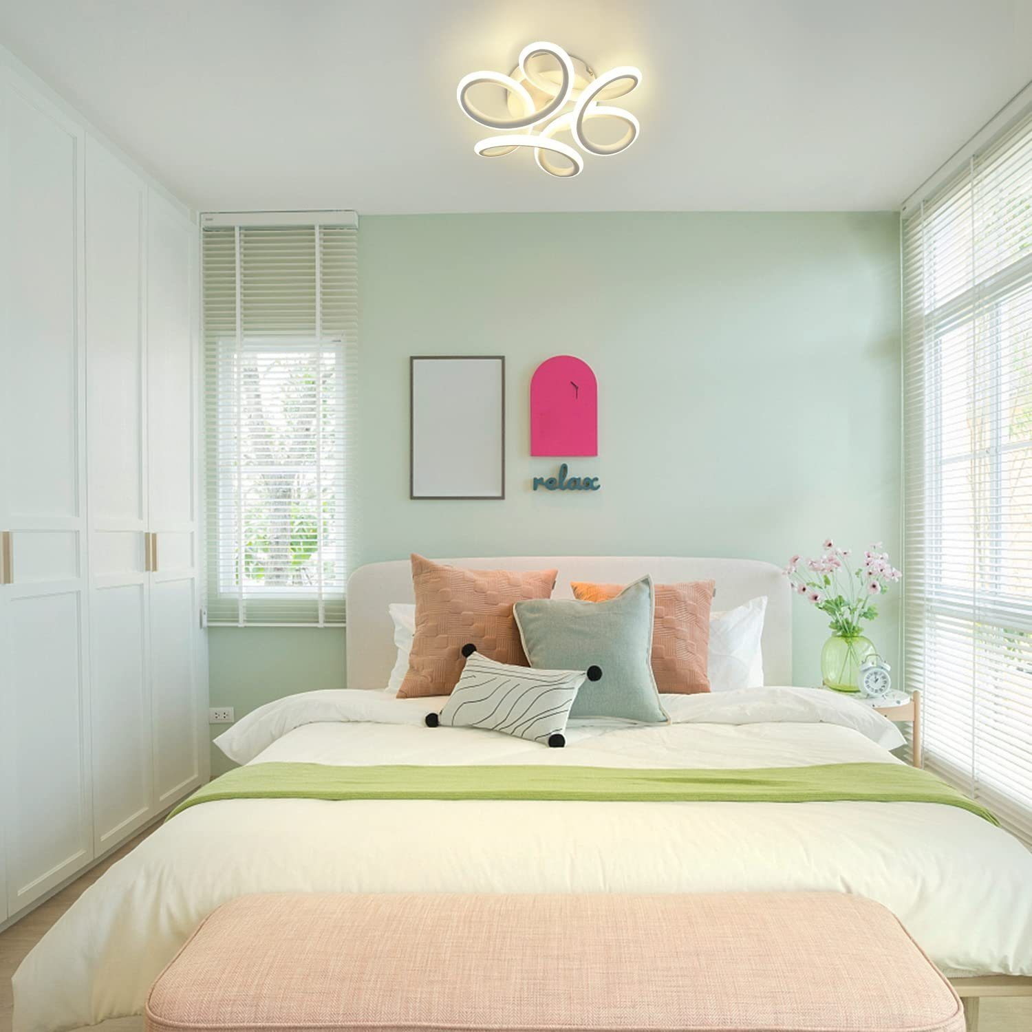 Dormitorio con cama blanca, manta verde y banco rosa. La pared es verde menta.