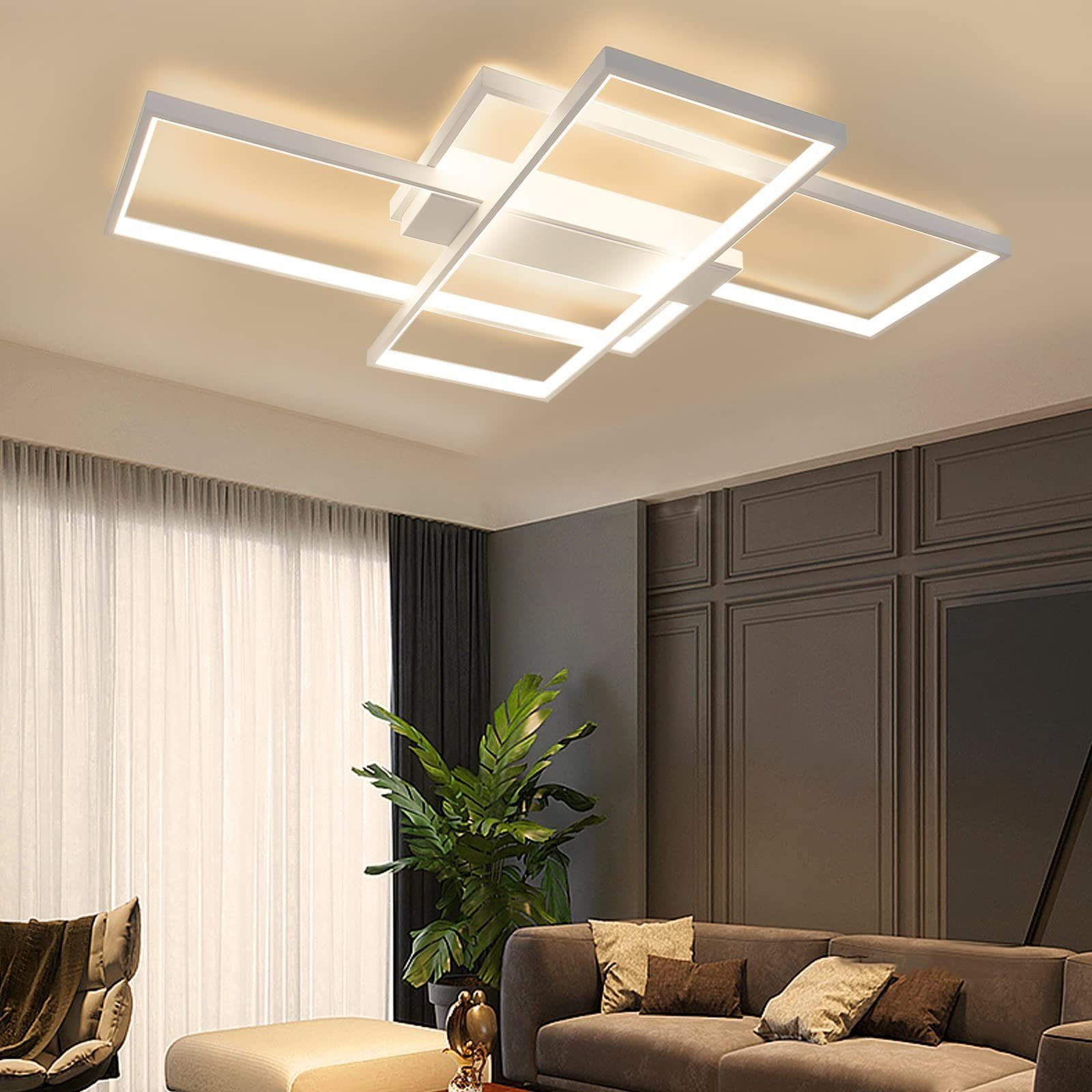Una moderna lámpara de techo con un diseño rectangular blanco. También hay un sofá y plantas en la habitación.