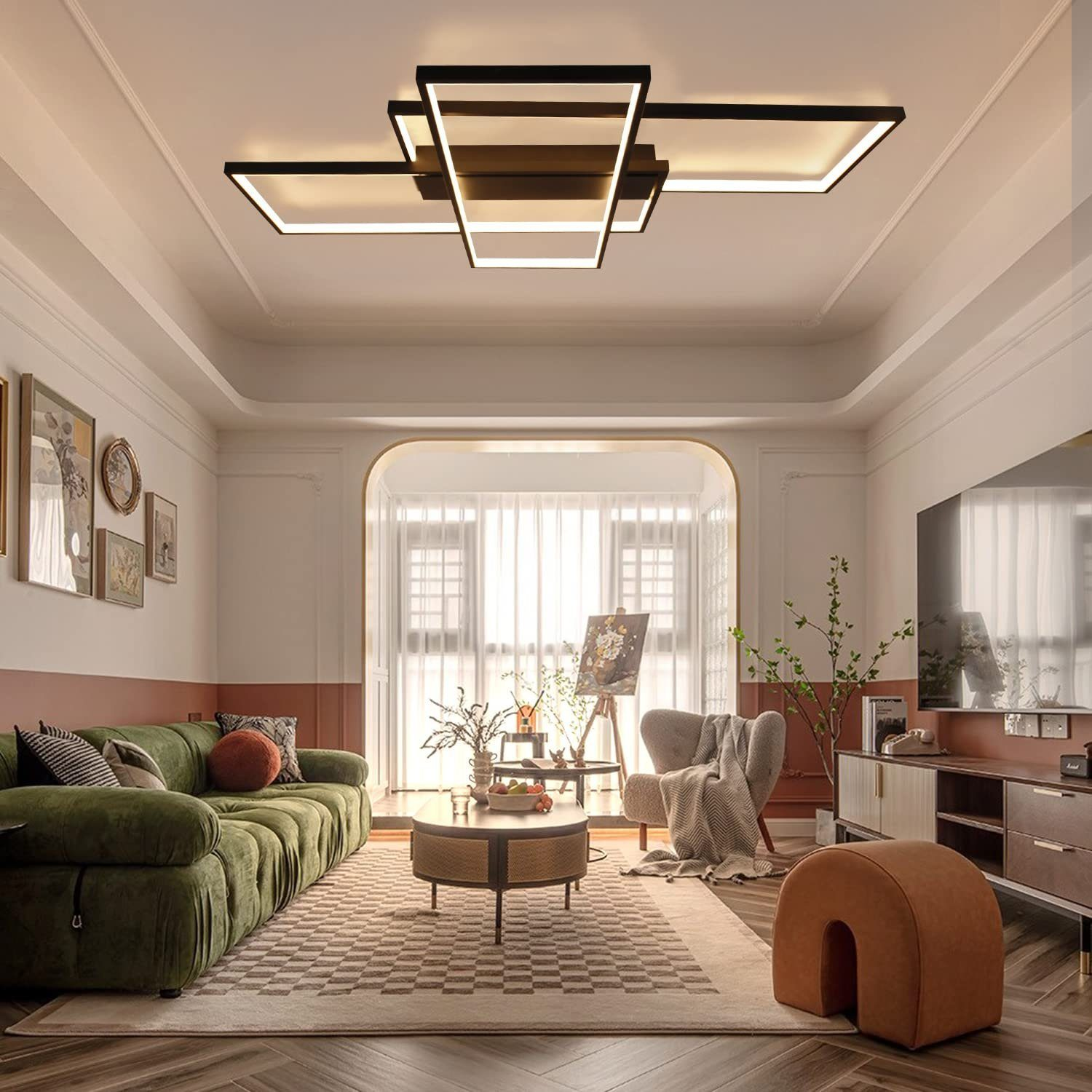 Salon z zieloną sofą, sztuką i nowoczesnym oświetleniem sufitowym. Dominują neutralne kolory.