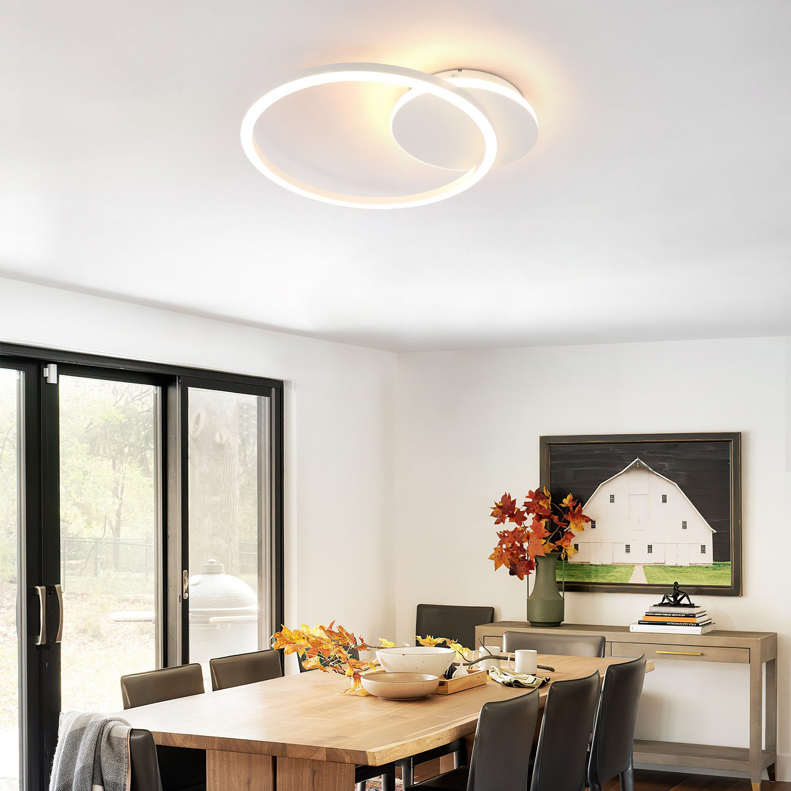 Una moderna lámpara de techo blanca en un comedor. La luz tiene un diseño de bucle, con una mesa de comedor debajo.