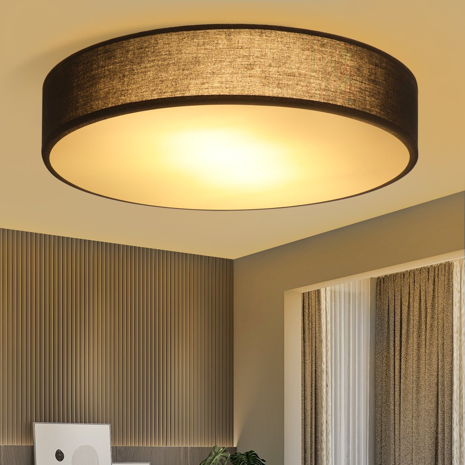 Una lámpara de techo redonda y oscura que ilumina una habitación con cortinas y un panel de madera.