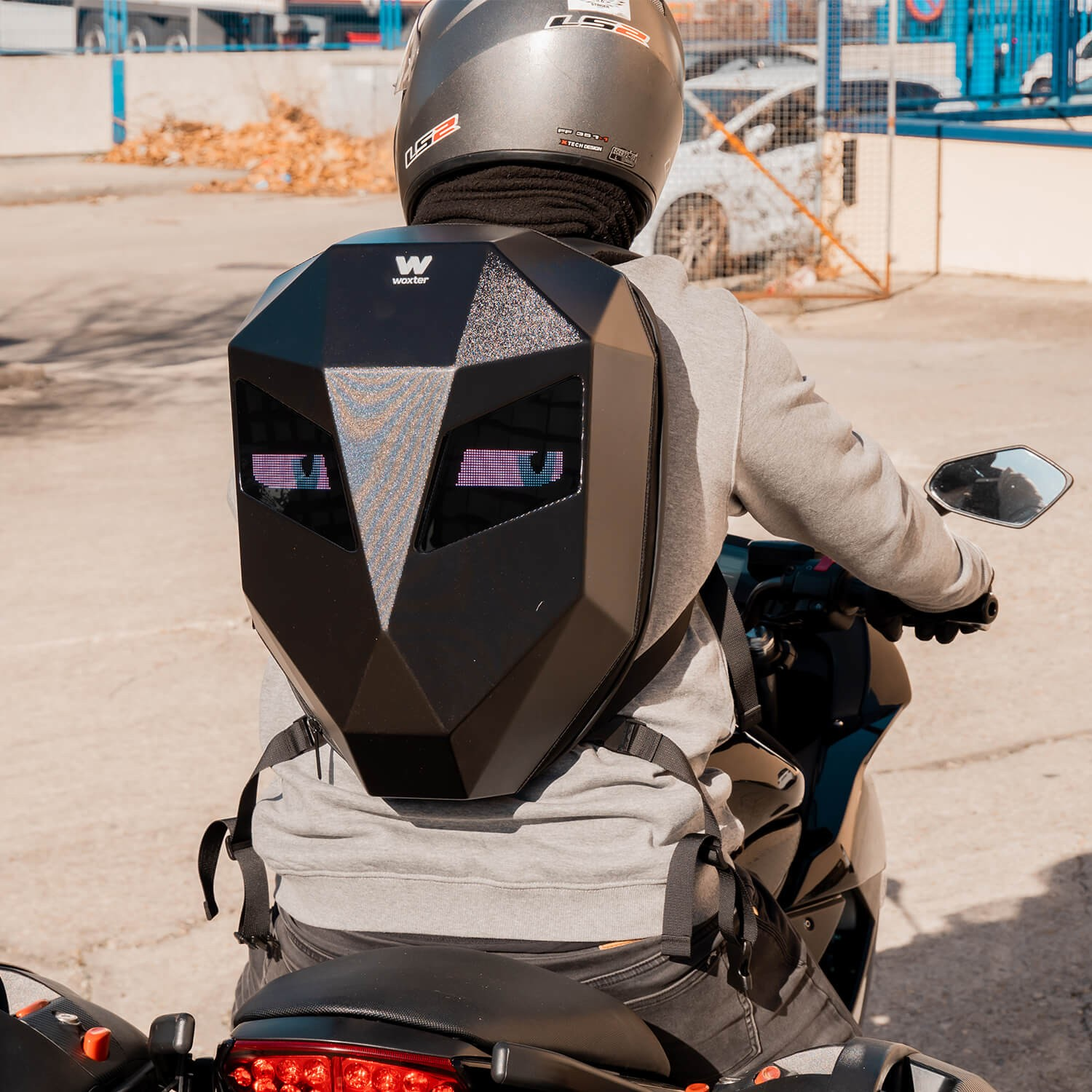 Persona en una moto con una mochila geométrica negra con ojos iluminados.