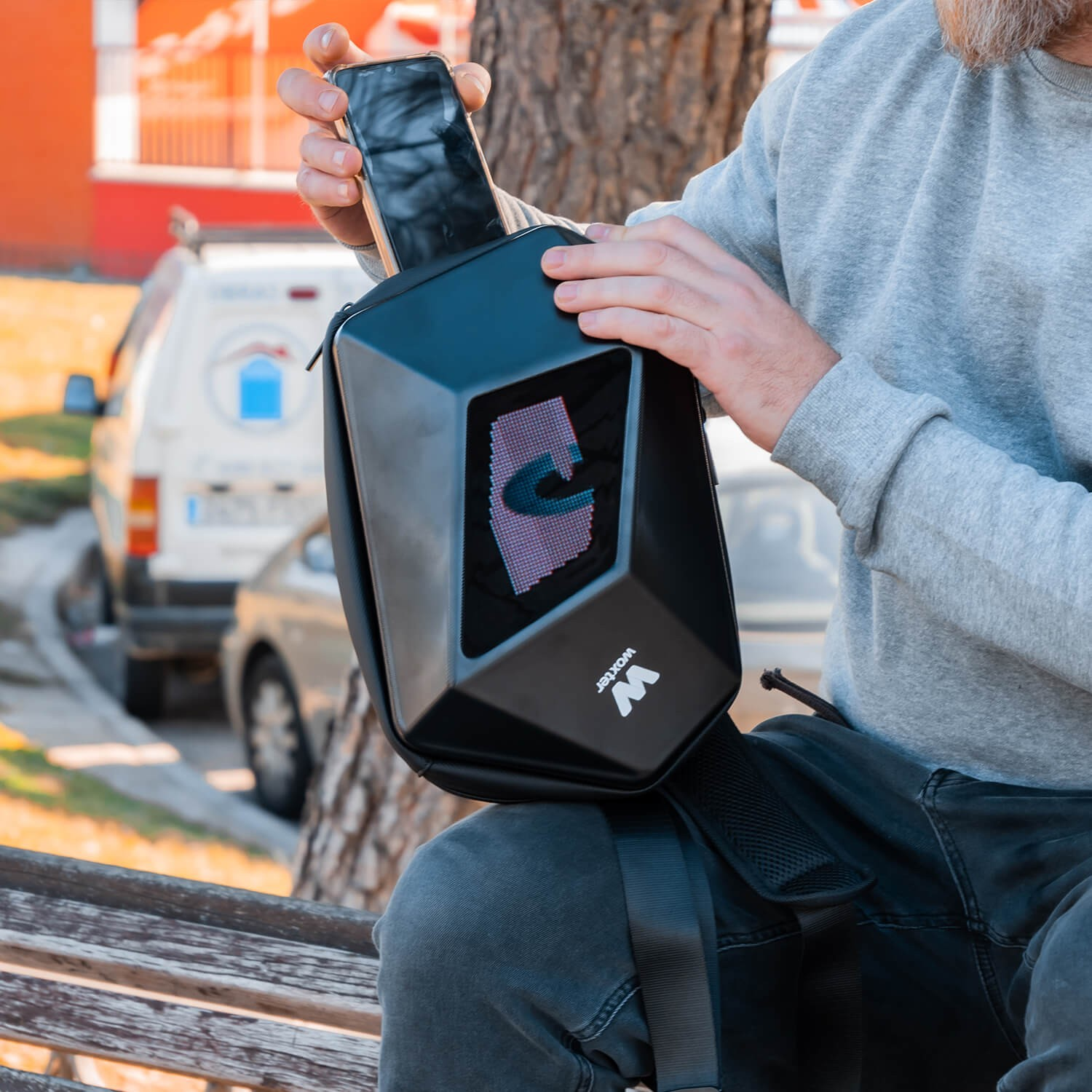 Una persona sostiene un teléfono frente a una bolsa negra con pantalla.