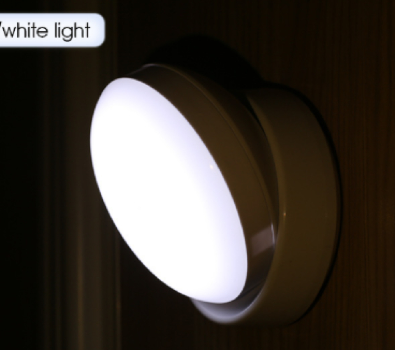 Eine weiße Leuchte, die weißes Licht ausstrahlt, an einer dunkelbraunen Holzwand montiert.