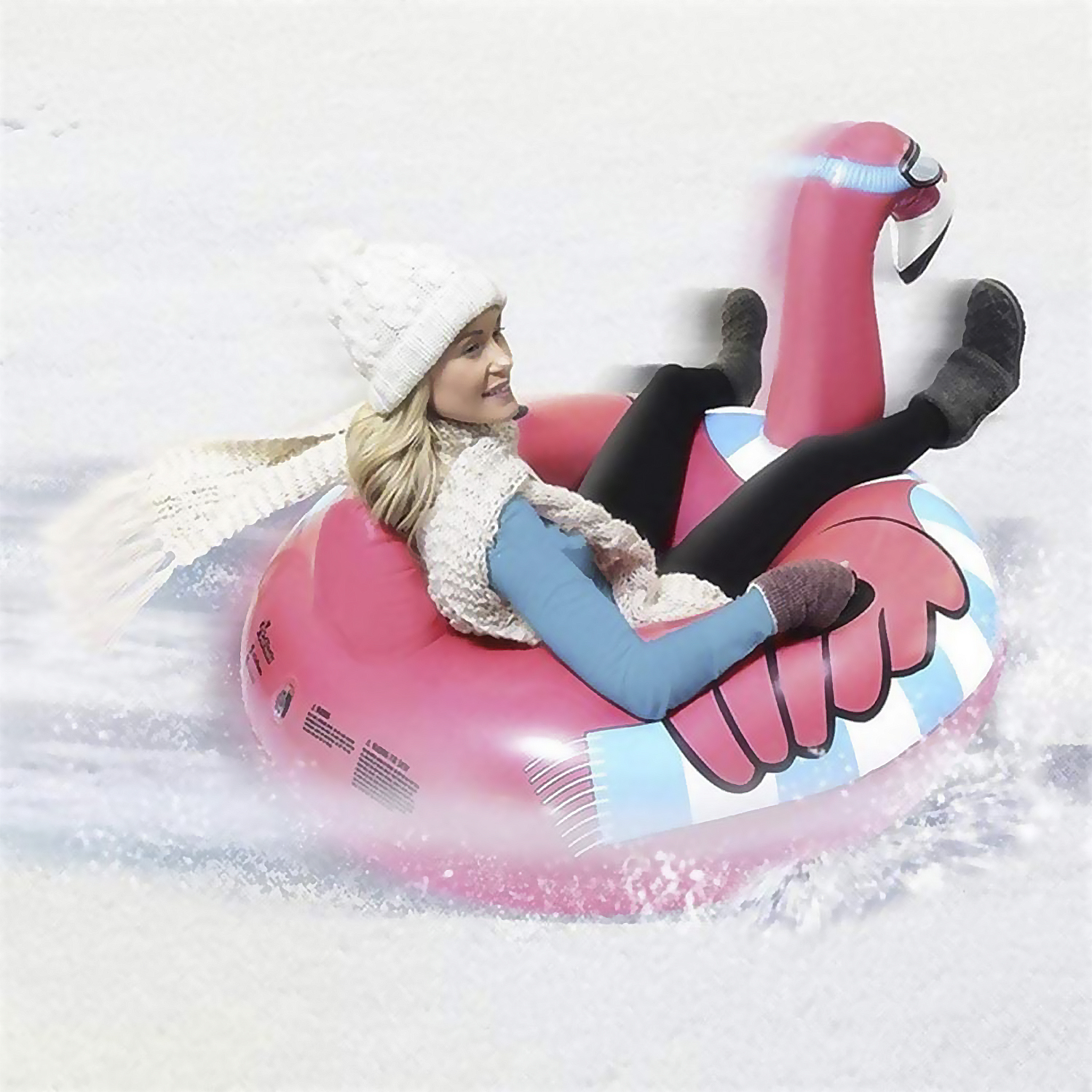 Donna su un galleggiante fenicottero rosa nella neve. Indossa cappello e sciarpa bianchi. Neve.