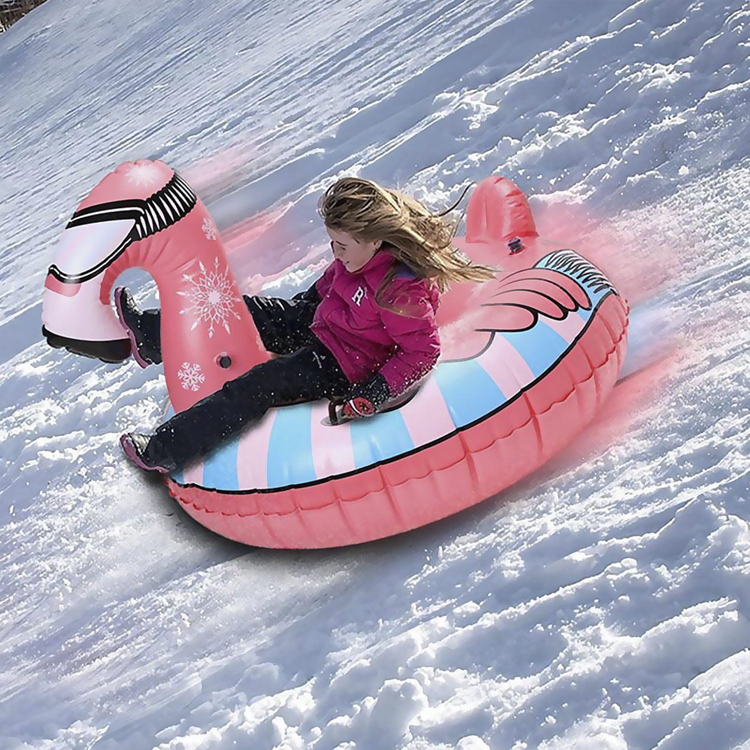 Ragazza scivola giù da un pendio innevato su un gonfiabile rosa a forma di fenicottero.